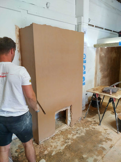 Apprentice applying plaster to a wall during a hands-on skimming course in a workshop setting.