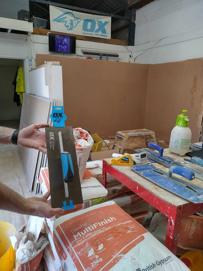 Plastering tools and materials in a workshop, showcasing an OX level and various plastering equipment.